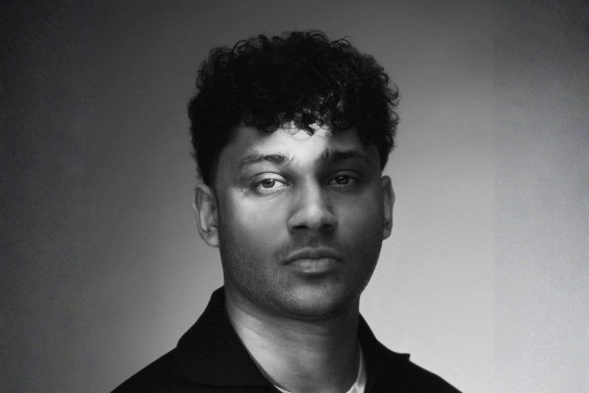 Black-and-white studio headshot of a young man with curly dark hair, facing the camera.